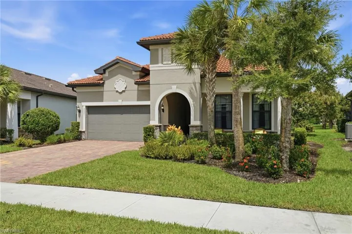 Stucco exterior with a tile roof, arched entryway, and an attached two-car garage