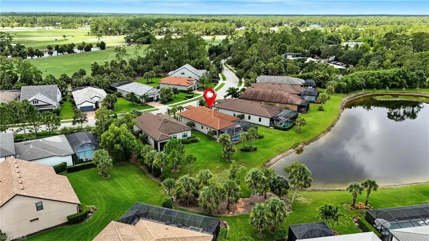 Waterfront residence with a screened pool enclosure, lush landscaping, and a tile roof