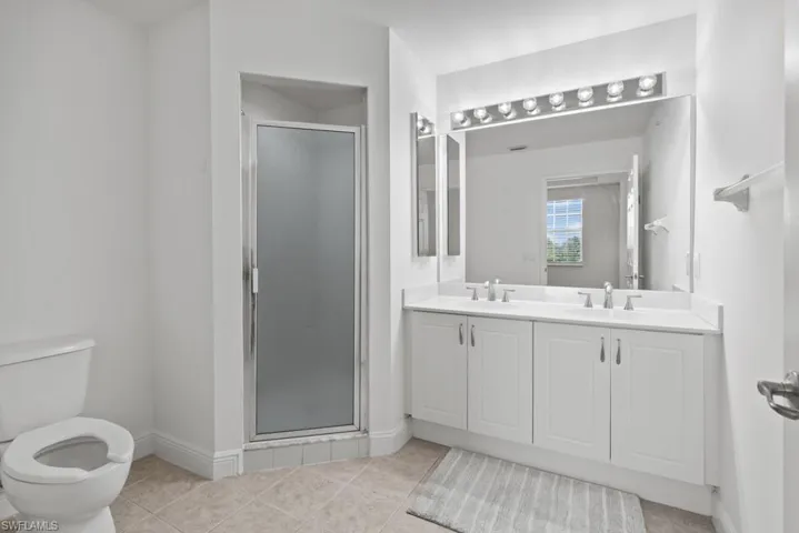Full bathroom featuring baseboards, tile patterned flooring, a sink, and a shower stall