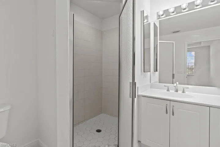 Bathroom featuring vanity, toilet, and a shower stall