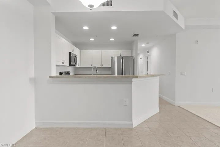 Kitchen featuring visible vents, a peninsula, appliances with stainless steel finishes, and white cabinetry
