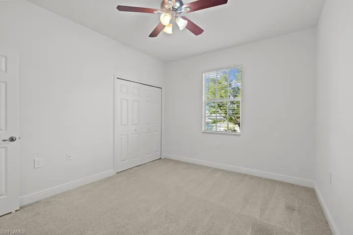 Unfurnished bedroom with baseboards, ceiling fan, a closet, and light colored carpet