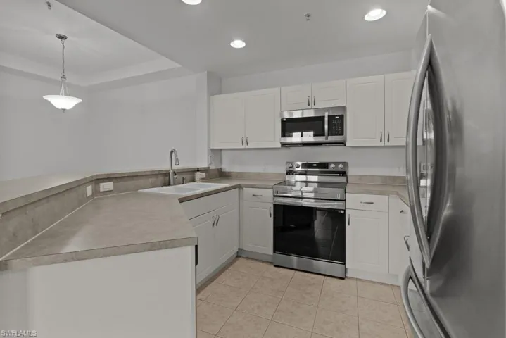 Kitchen featuring white cabinetry, appliances with stainless steel finishes, pendant lighting, and a sink