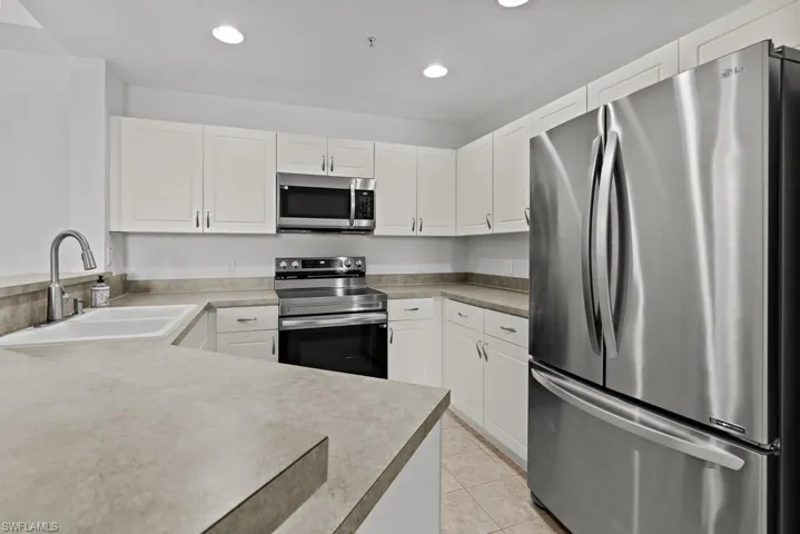 Kitchen featuring light tile patterned floors, recessed lighting, appliances with stainless steel finishes, white cabinetry, and a sink