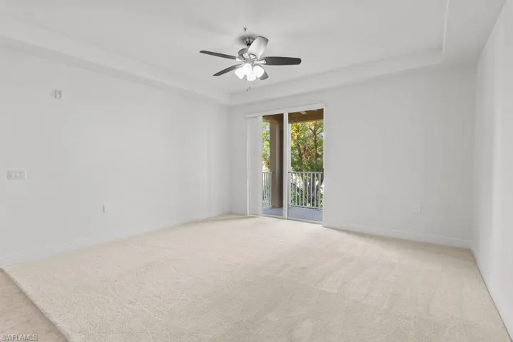 Empty room featuring a tray ceiling, light colored carpet, and baseboards