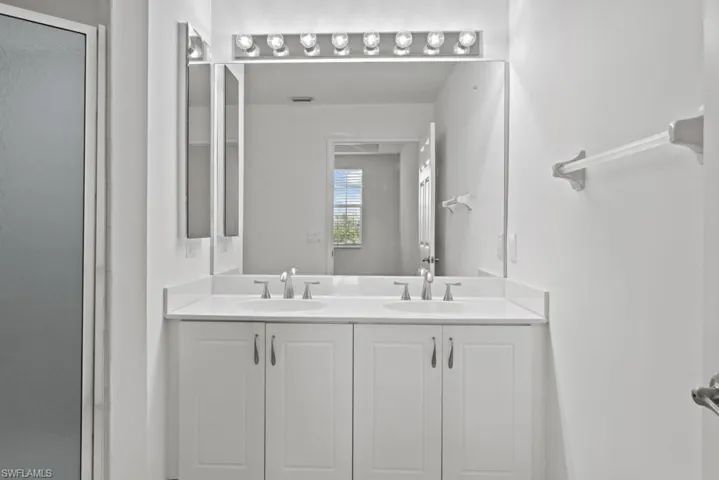 Full bathroom featuring double vanity, a stall shower, and a sink