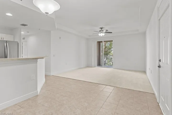 Unfurnished living room with baseboards, visible vents, a ceiling fan, and light colored carpet