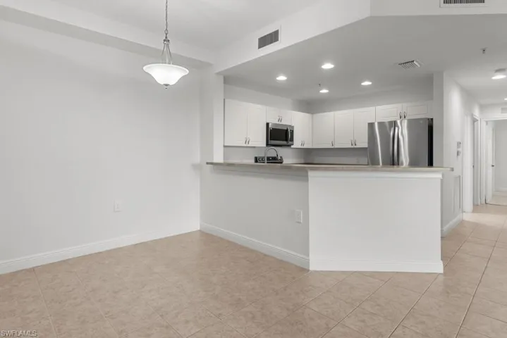 Kitchen featuring stainless steel appliances, a peninsula, visible vents, white cabinets, and pendant lighting