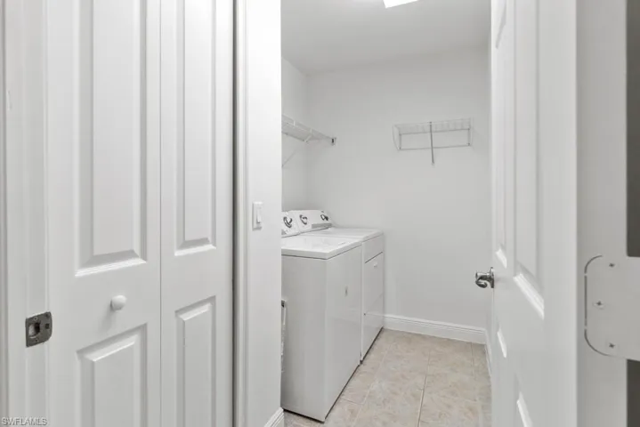 Laundry area featuring laundry area, baseboards, washer and dryer, and light tile patterned flooring