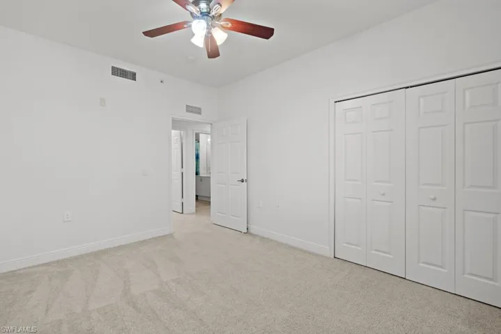 Unfurnished bedroom with light carpet, baseboards, visible vents, and a closet