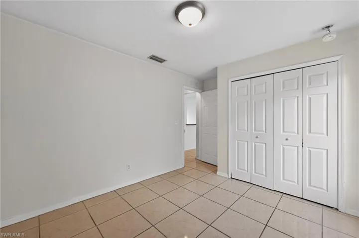 Neutral tone tile flooring, white walls, and a ceiling-mounted light fixture