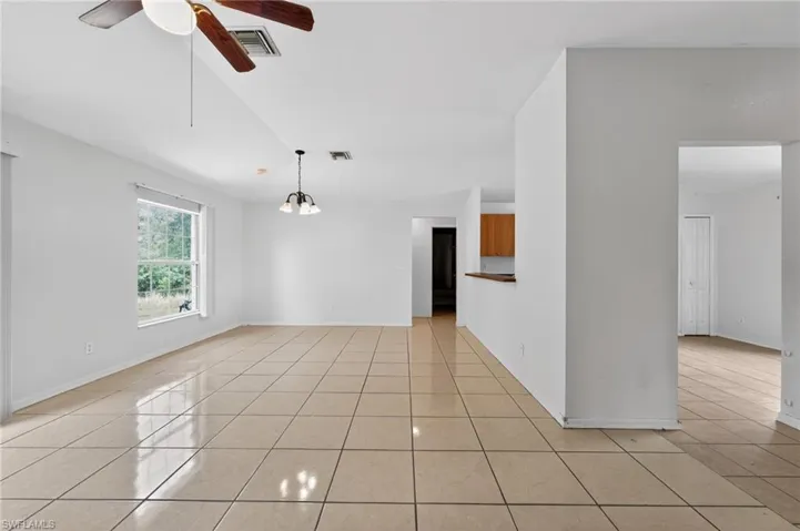 Spacious room featuring tile flooring, a ceiling fan, a window providing exterior views, and a pendant light fixture