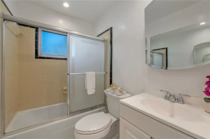 Full bathroom with large vanity, combined bath / shower with glass door, and toilet