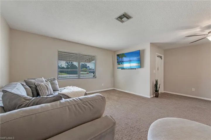 Living room featuring a textured ceiling, carpet floors, and ceiling fan