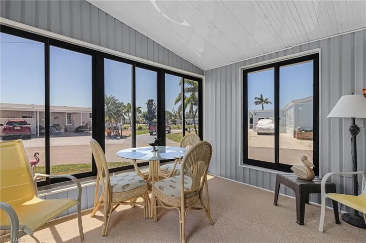 Sunroom with carpet floors, wallpapered walls, and lofted ceiling