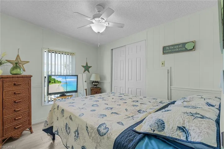 Bedroom with light wood-style floors, a closet, a textured ceiling, and ceiling fan