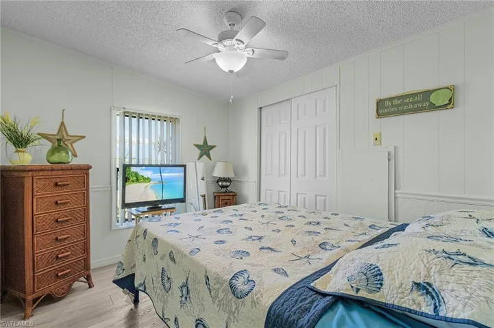 Bedroom with light wood-style floors, a closet, ceiling fan, and a textured ceiling