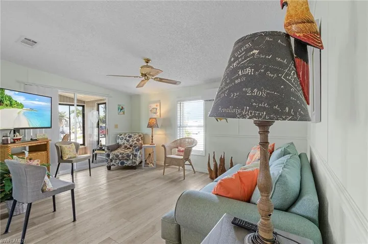 Living room with a textured ceiling, wood finished floors, ceiling fan, and visible vents