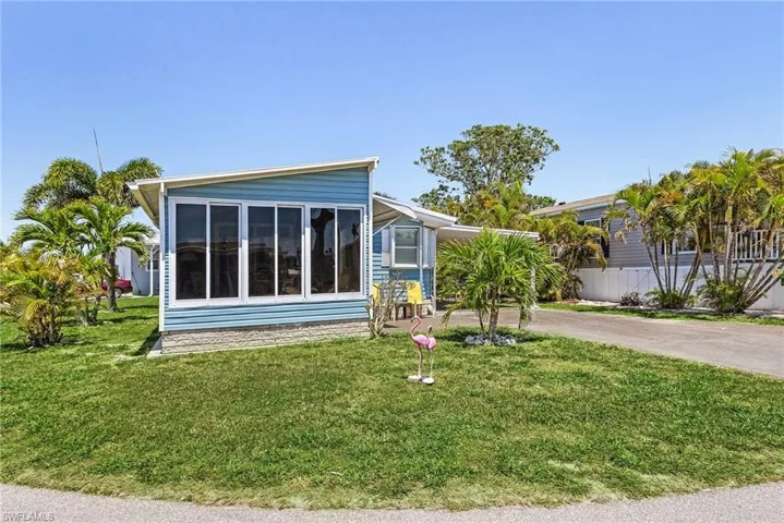 View of home's exterior with a sunroom, driveway, and a lawn
