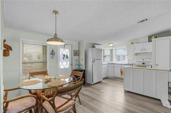 Dining space with visible vents, a textured ceiling, crown molding, and light wood-style flooring