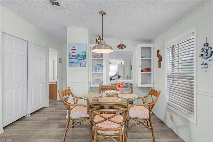 Dining area with plenty of natural light, light wood-style floors, a textured ceiling, and crown molding