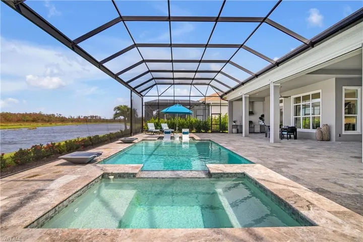 View of swimming pool featuring a patio area, a lanai, an in ground hot tub, and a water view