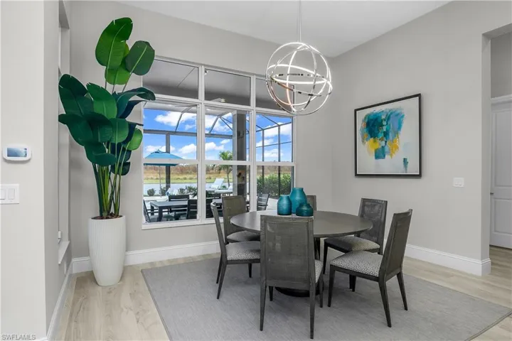 Dining room with an amazing view, designer chandelier, chandelier and light wood-type flooring.