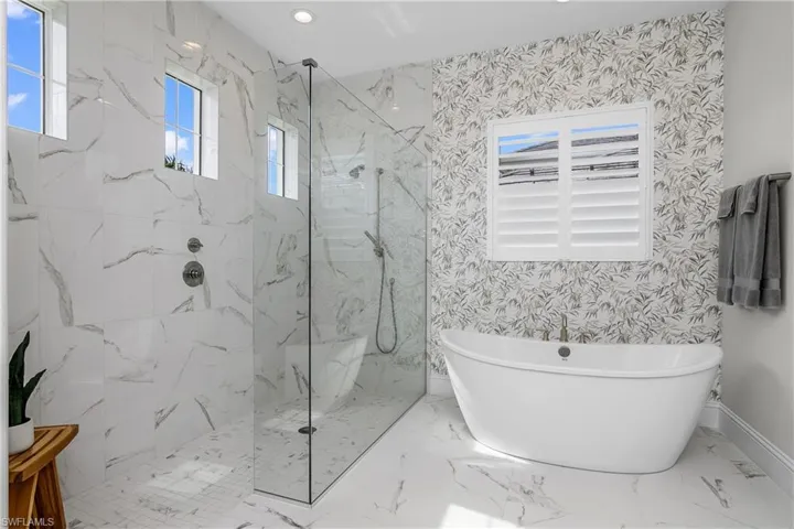Bathroom with lots of natural light, stand alone tub, and walk in shower