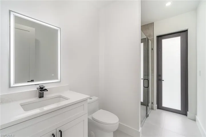 Bathroom with tile patterned flooring, toilet, vanity, and an enclosed shower