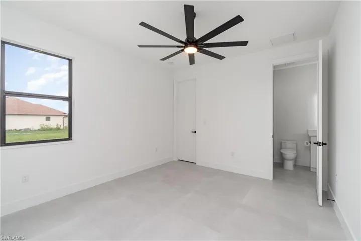 Unfurnished bedroom with ceiling fan, connected bathroom, and light tile patterned floors