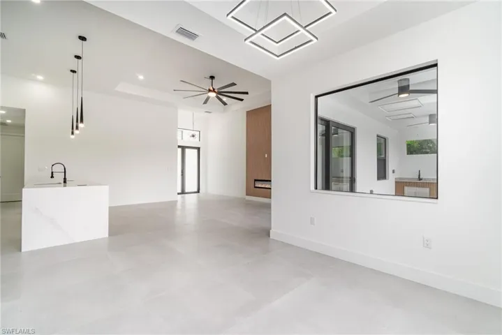 Unfurnished living room featuring sink, ceiling fan, and a tray ceiling
