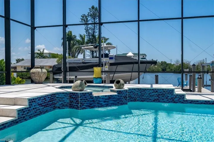 View of swimming pool featuring a patio area, an in ground hot tub, and glass enclosure