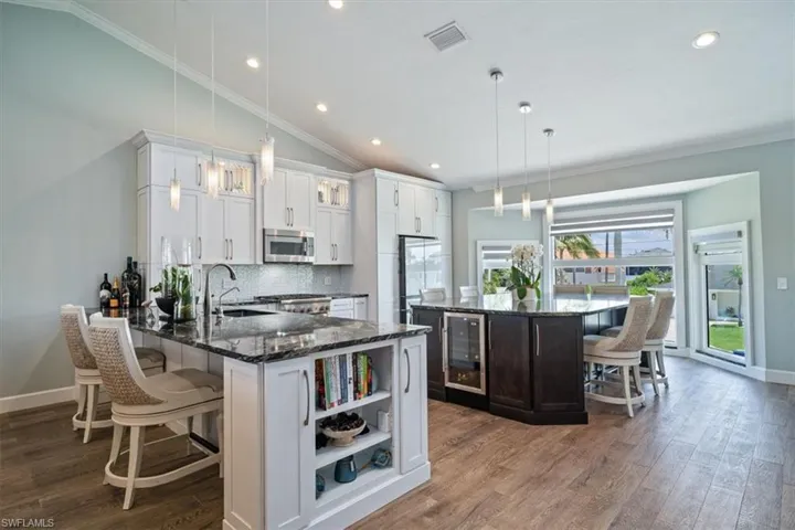 Kitchen featuring appliances with stainless steel finishes, sink, white cabinetry, lofted ceiling, and decorative light fixtures