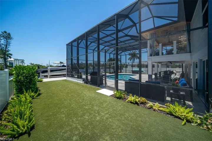 View of yard with ceiling fan, glass enclosure, and a patio area