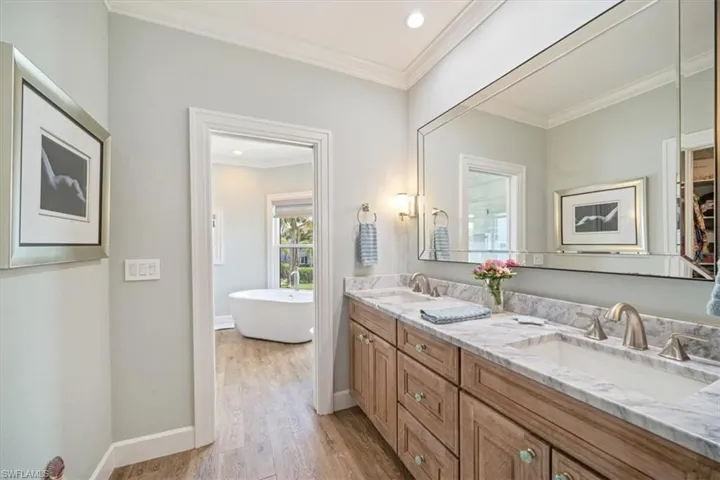 Bathroom with vanity, ornamental molding, hardwood / wood-style flooring, and a bathing tub