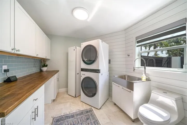 Clothes washing area with stacked washing maching and dryer, sink, and wooden walls