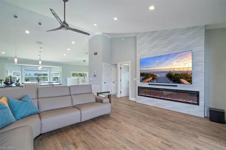 Living room with hardwood / wood-style flooring, crown molding, a fireplace, a towering ceiling, and ceiling fan