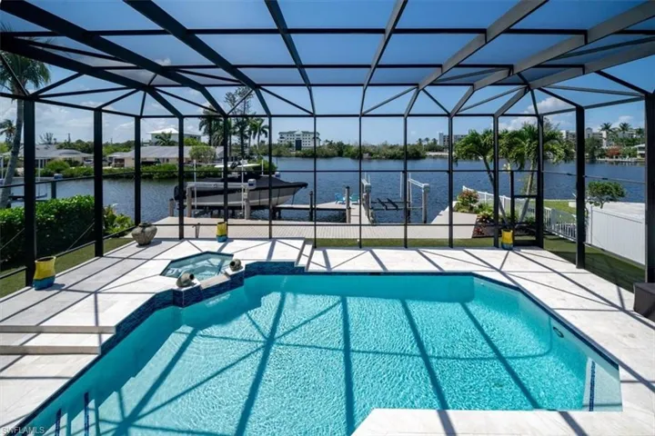 View of swimming pool featuring an in ground hot tub, a patio area, a lanai, a water view, and a boat dock