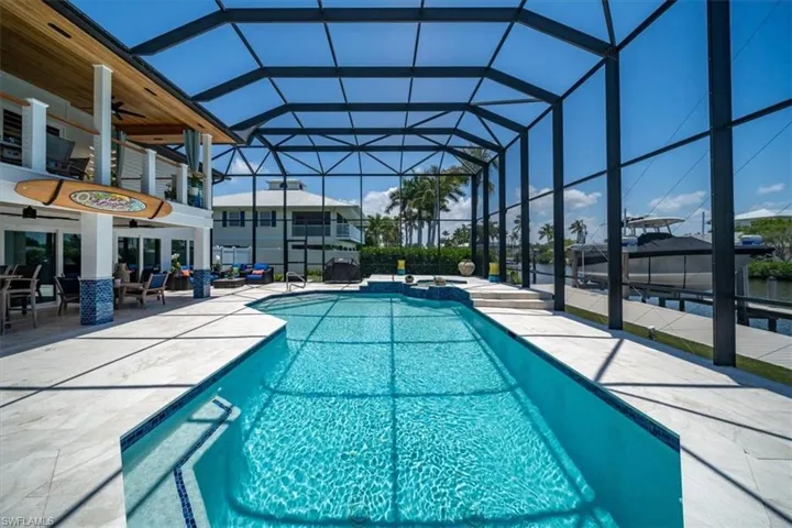 View of pool featuring a patio area, ceiling fan, and glass enclosure