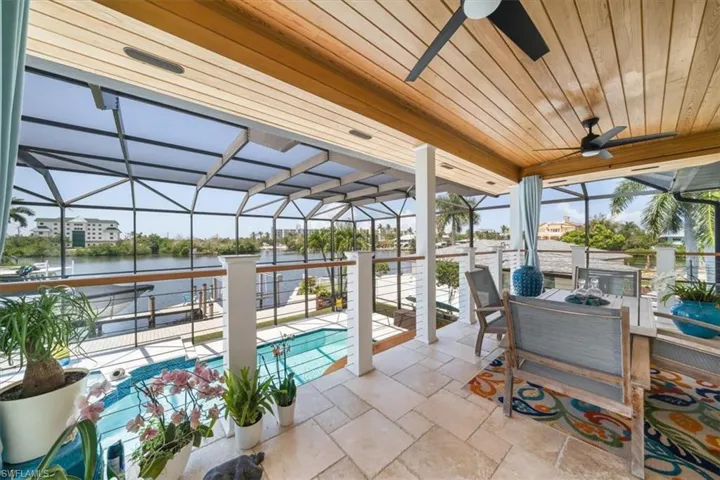 View of patio / terrace featuring a lanai, a water view, and ceiling fan