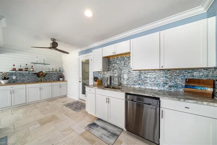 Kitchen with sink, dishwasher, white cabinets, and ornamental molding