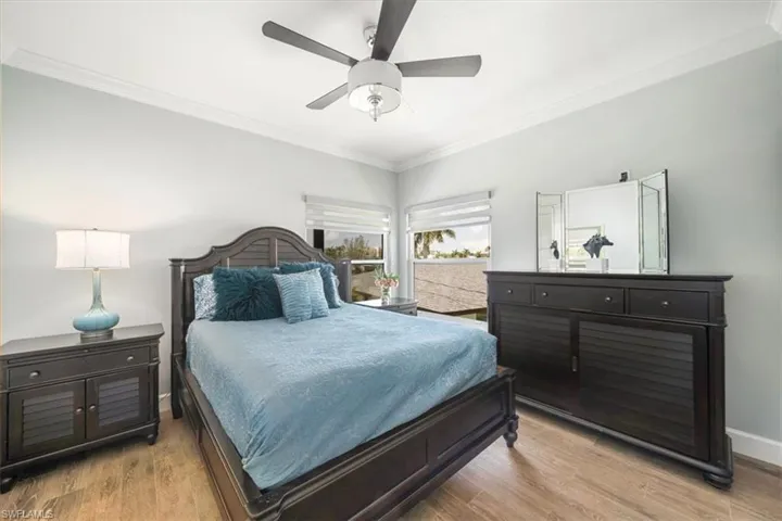 Bedroom with light hardwood / wood-style floors, ornamental molding, and ceiling fan