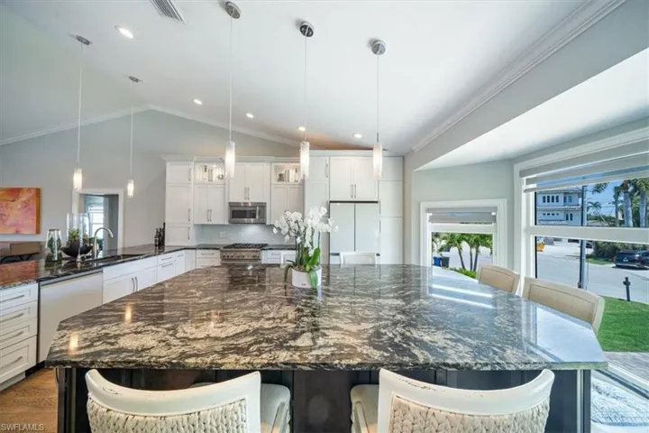 Kitchen with lofted ceiling, appliances with stainless steel finishes, and hanging light fixtures