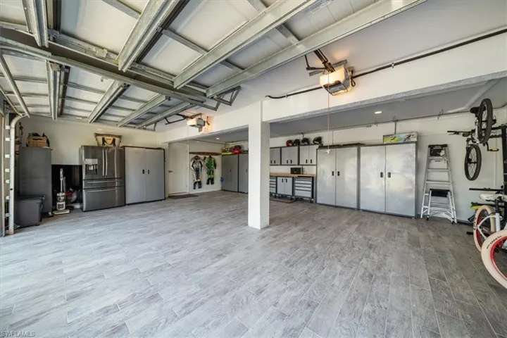 Garage featuring a garage door opener and stainless steel fridge