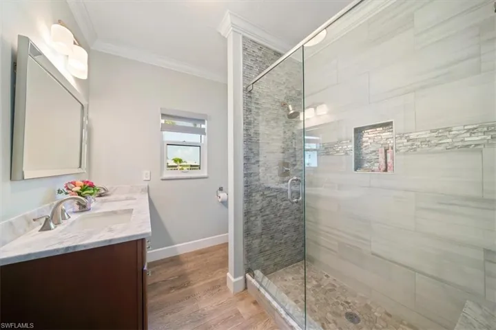 Bathroom with vanity, ornamental molding, hardwood / wood-style flooring, and walk in shower