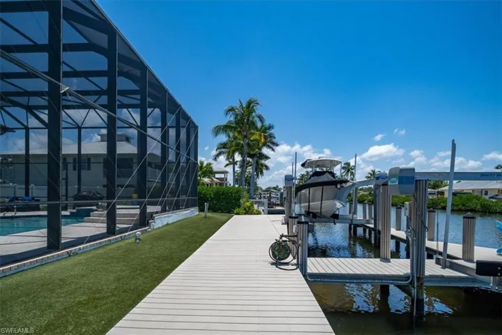 Dock area featuring a lawn, a water view, and glass enclosure