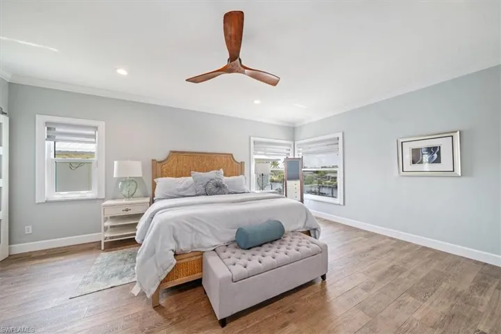 Bedroom featuring multiple windows, hardwood / wood-style floors, crown molding, and ceiling fan