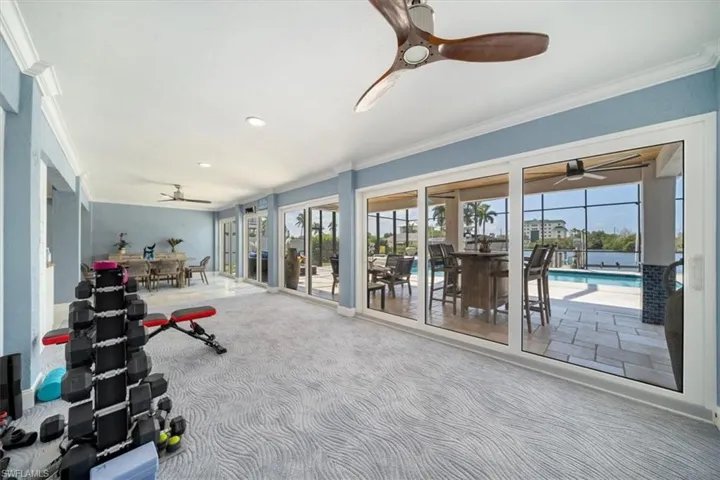 Exercise area with ornamental molding, carpet floors, a pool, and ceiling fan