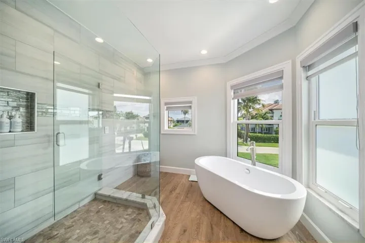 Bathroom with crown molding, hardwood / wood-style flooring, and independent shower and bath