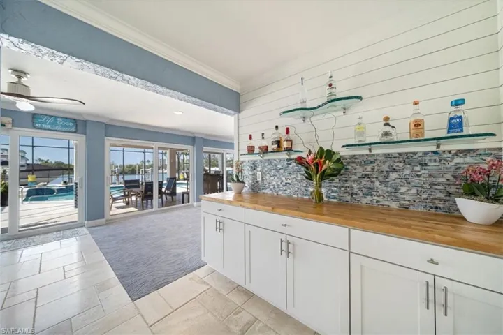 Kitchen with decorative backsplash, white cabinets, ceiling fan, wood counters, and ornamental molding